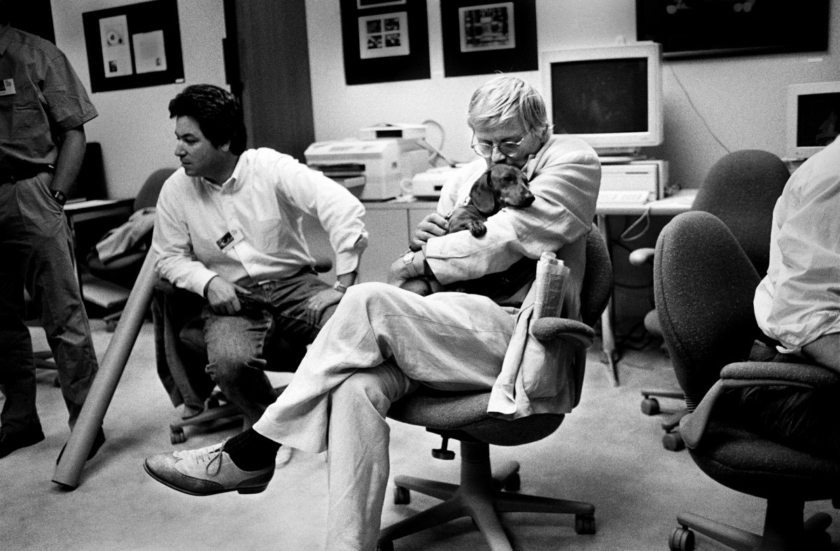 The Painter David Hockney Rests During a Photoshop Class. Mountain View, California, 1990. As digital technology grew more powerful, Silicon Valley resembled what Paris in the twenties must have been like.  Artists arrived from all over the world, eager to experiment. Musicians like Peter Gabriel and Herbie Hancock were early adopters. George Lucas was a pioneer, as was Francis Coppola, and there were many others. The cultural ground was shifting, with the avant-garde gathering to push new ideas into the culture. Here, British painter David Hockney, holding one of his beloved dachshunds, attends Russell Brown’s 1990 Adobe Photoshop Invitational, where he learned how to use the first release version of Photoshop. 
