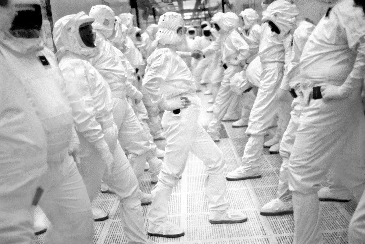 Exercise Break at Intel Fab 11x. Rio Rancho, New Mexico, 1998. Workers inside Intel’s largest chip fabrication plant exercise and stretch as part of their normal workday break time. They produce 5 chips a second, 24 hours a day. Many of the workers are from the nearby Pueblo tribe of Native Americans, who maintain their traditions when not working with new technology. After work, in good weather, many tend their corn and bean fields with their families before dinner. An industry powerhouse, they helped Microsoft Windows become the dominant operating system and today Intel chips run most of the PC's in the world. Founded by industry legends Gordon Moore and Robert Noyce, Andy Grove was their first employee. Moore posited “Moore’s Law” which predicted the number of transistors placed on chips would double approximately every two years. Noyce is co-creator of the microchip that gave Silicon Valley its name and which fueled its growth. Andy Grove become CEO and led Intel through a long period of tremendous growth. He became a mentor to Steve Jobs as Jobs began his quest for redemption after Apple. Although Jobs hated Microsoft Windows and was unhappy about Intel's support of Microsoft, he acknowledged the Pentium chip as a true innovation and said it was 