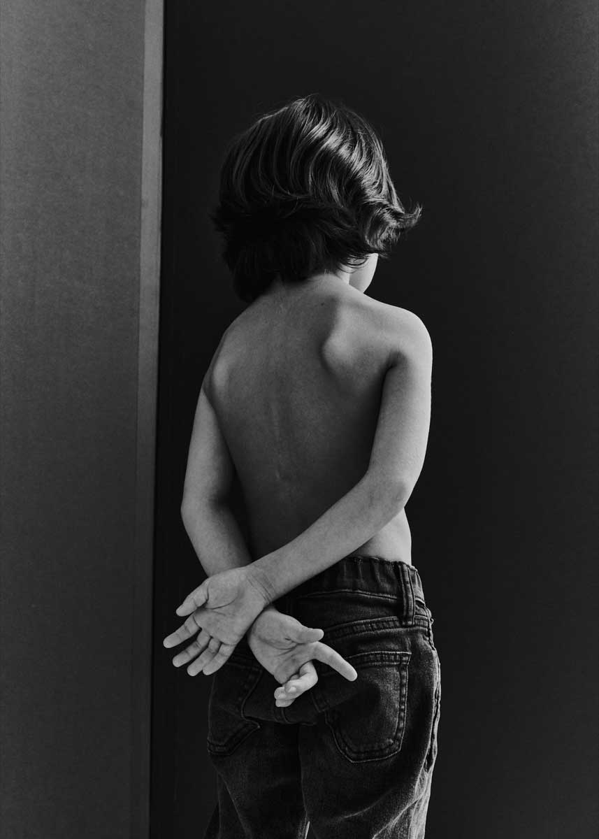 Black and white portrait of a young boy with his back to the camera